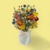 colourful dried flower bouquet with orange, yellow, white and blue blooms against a soft yellow background